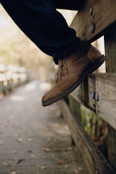 时尚特写：棕色绒面革靴子置于户外木栅栏上