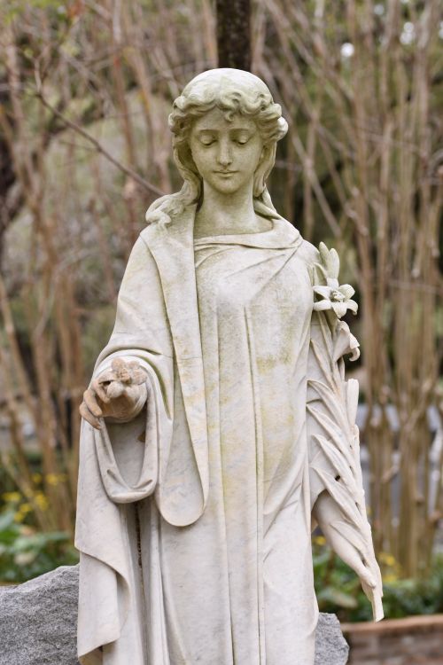 Free Beautiful marble statue of a serene female figure holding a flower, outdoors. Stock Photo