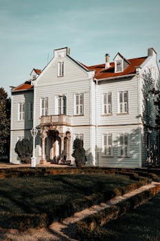 Beautiful vintage mansion with a red roof and lush garden front yard, perfect for luxury real estate.