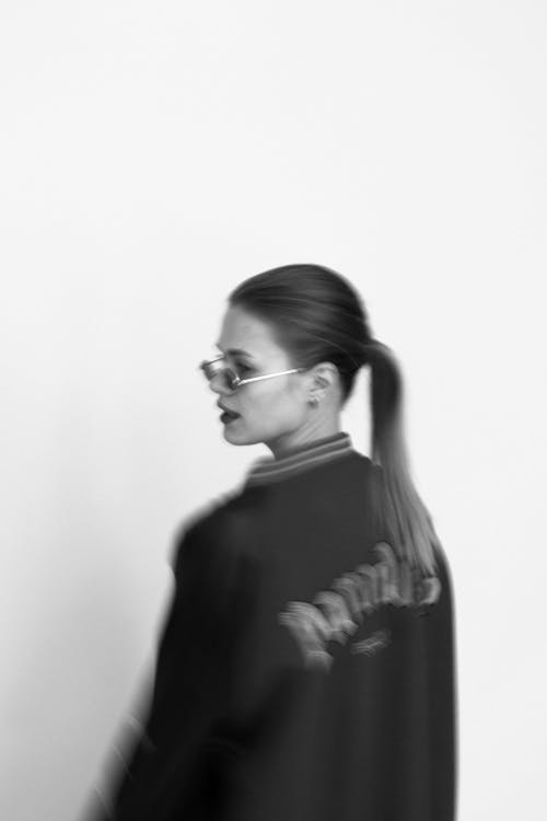 Grayscale Photo of a Woman in a Jacket Wearing Sunglasses
