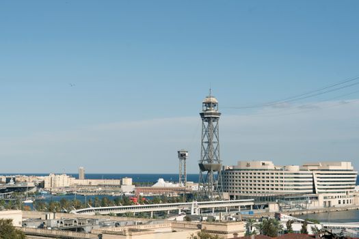 Aerial cityscape of Barcelona harbor with iconic towers and clear blue sky.