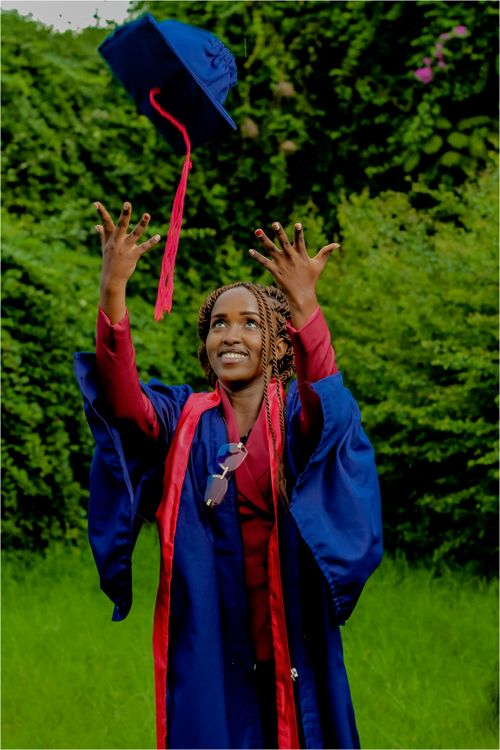 Free Excited graduate throwing cap in garden, celebrating achievement. Stock Photo