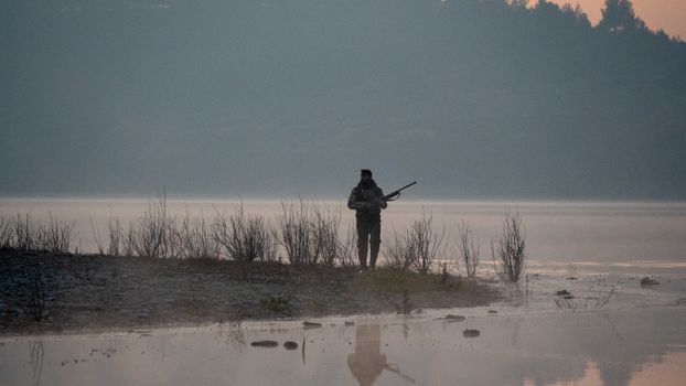 Man with a Rifle Waiting on Lakeshore