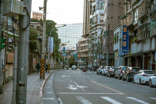 Free A busy urban street lined with parked cars and tall buildings in an Asian city. Stock Photo