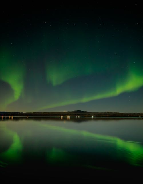 Free Captivating view of aurora borealis reflecting on a tranquil lake in Ölfus, Iceland under a starlit sky. Stock Photo