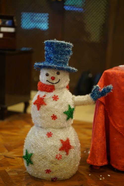 Free A cheerful snowman decoration adorned with colorful stars, perfect for indoor Christmas settings. Stock Photo