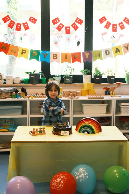 Free A child celebrating a birthday in a colorful classroom with cake and decorations. Stock Photo