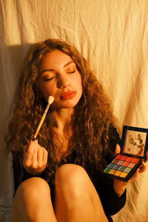 Close-Up Shot of a Curly-Haired Woman Holding a Makeup Brush
