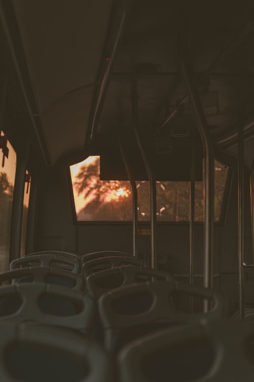 Free An empty urban bus interior captured at sunset, infused with warm, soft lighting creating a tranquil scene. Stock Photo
