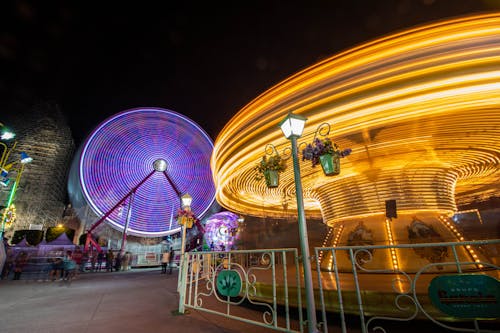 Illuminated Carousel and Ferris Wheel at Night