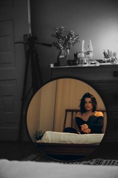 A woman reflected in a round mirror in a cozy Turkish bedroom.