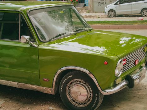 A polished green vintage car parked on an urban street, exemplifying classic style.