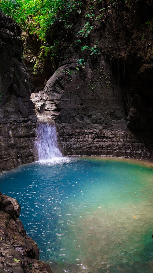 A Waterfalls Streaming on River Between Rock Formations