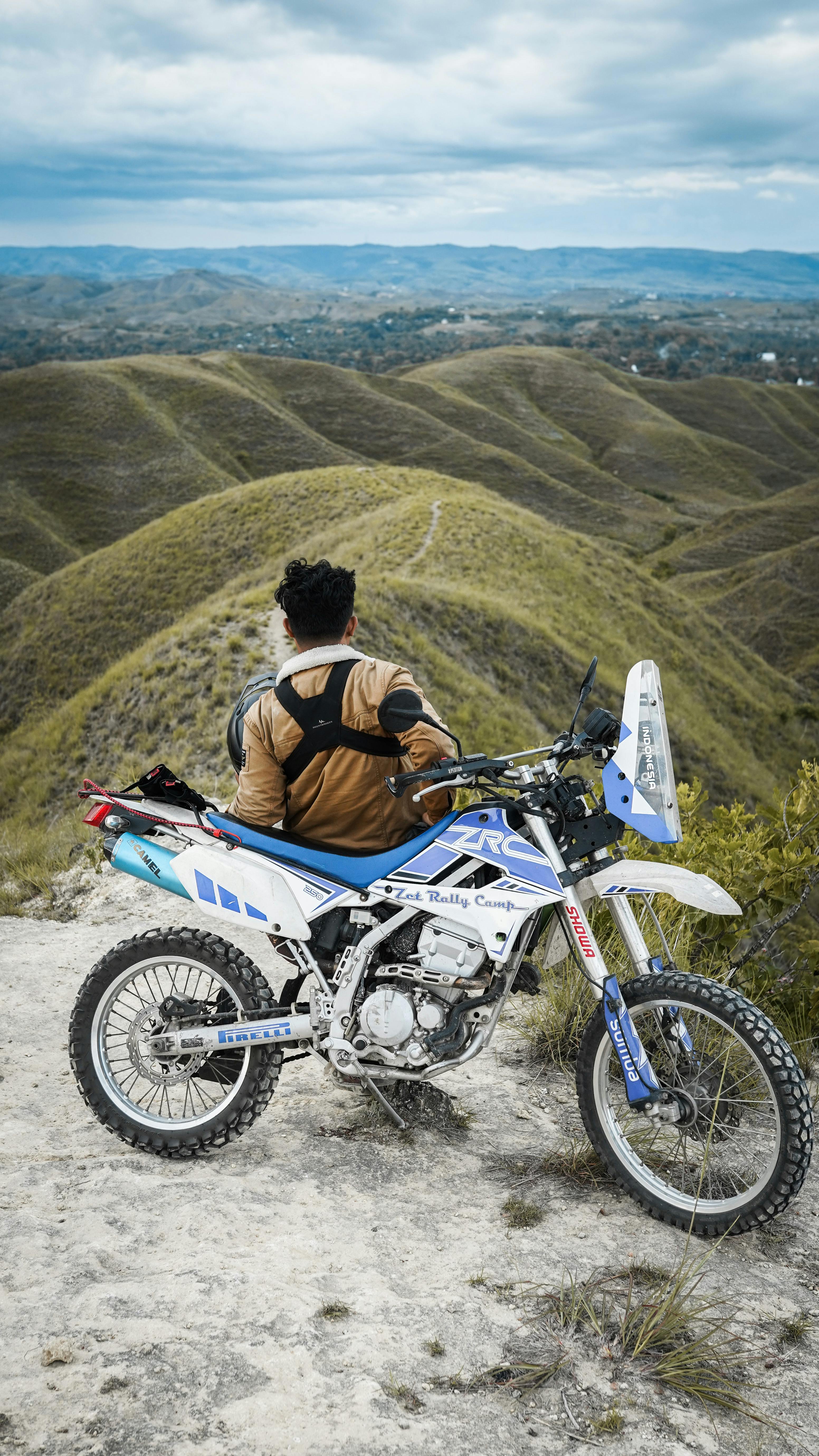 Man with Motorbike with Hills Landscape behind · Free Stock Photo