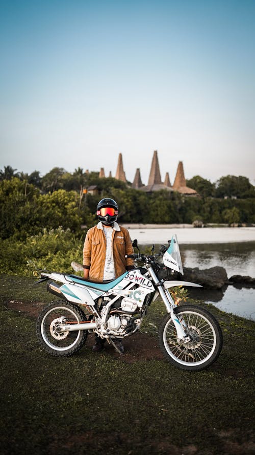 A Person in Brown Jacket Standing Near the Dirt Bike