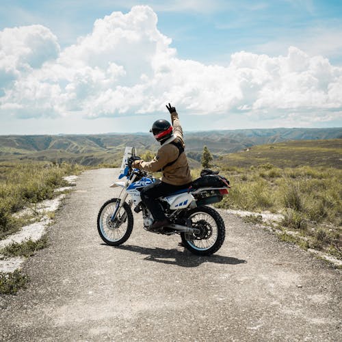 Man Riding a Motorcycle on a Paved Road in the Mountains