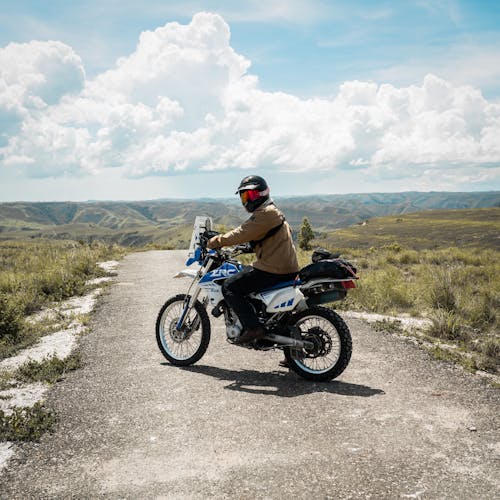 Man Riding a Motorbike in a Paved Road in the Mountains