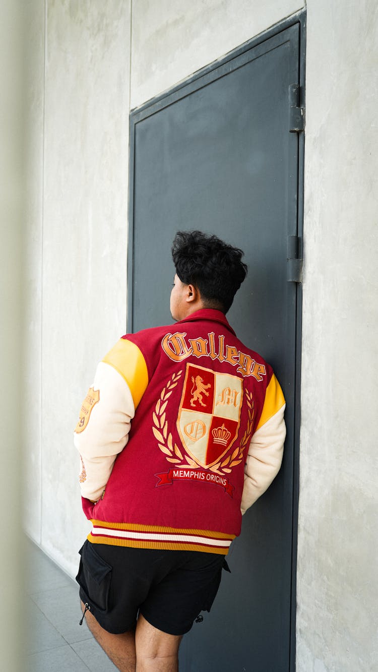 A Man In Red Varsity Jacket Leaning On The Door