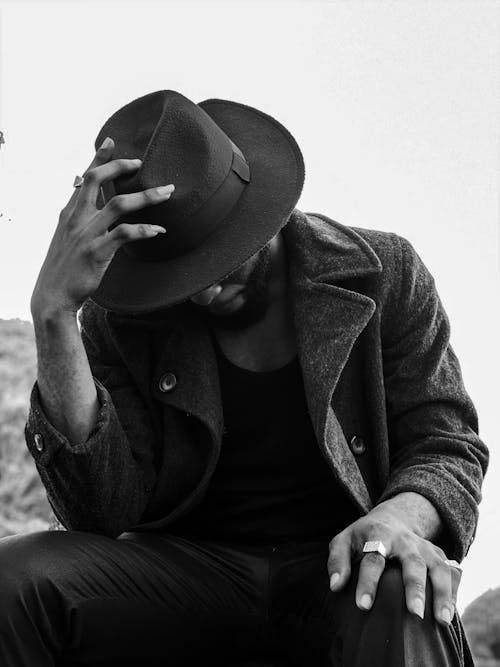 A Grayscale of a Man Wearing a Coat and a Fedora Hat