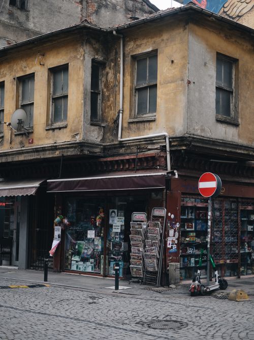 Free A vintage corner storefront in an urban area, showcasing weathered architecture and a newsstand display. Stock Photo