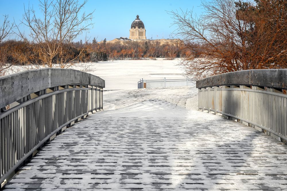 Snow-covered bridge and trees leading to Saskatchewan Legislative Building in Regina.