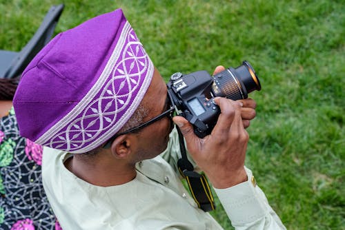 Man in Purple Bucharian Kippah Taking Photo with Dslr Camera