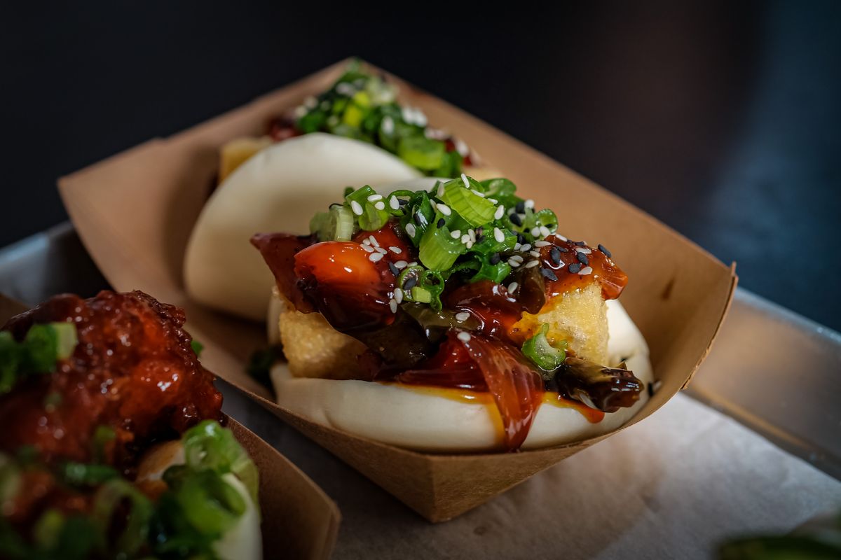 Steamed bao buns filled with glazed fried tofu, mushrooms, scallions and sesame in paper trays