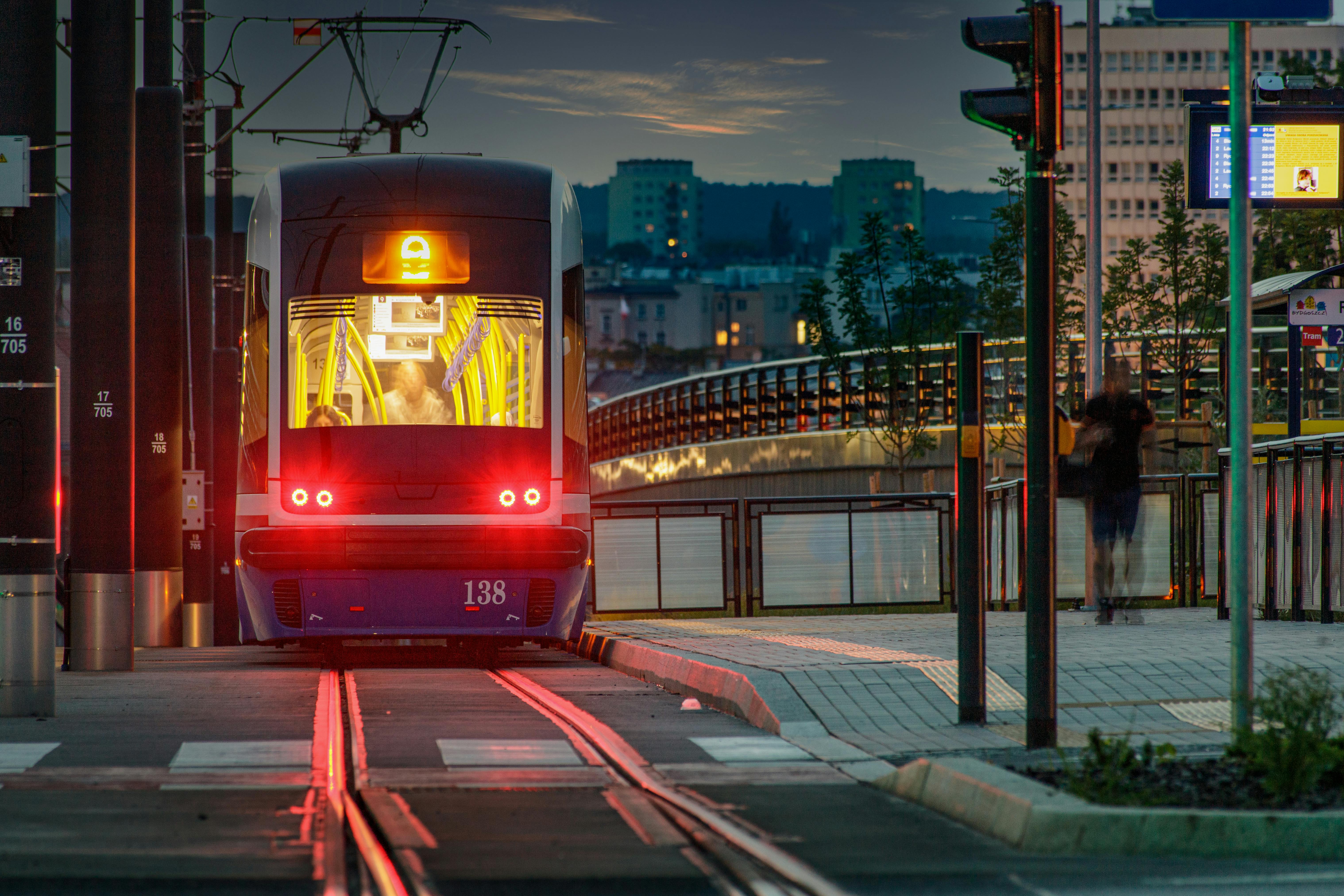 Tram approaching a station in Bydgoszcz at dusk with city lights glowing.