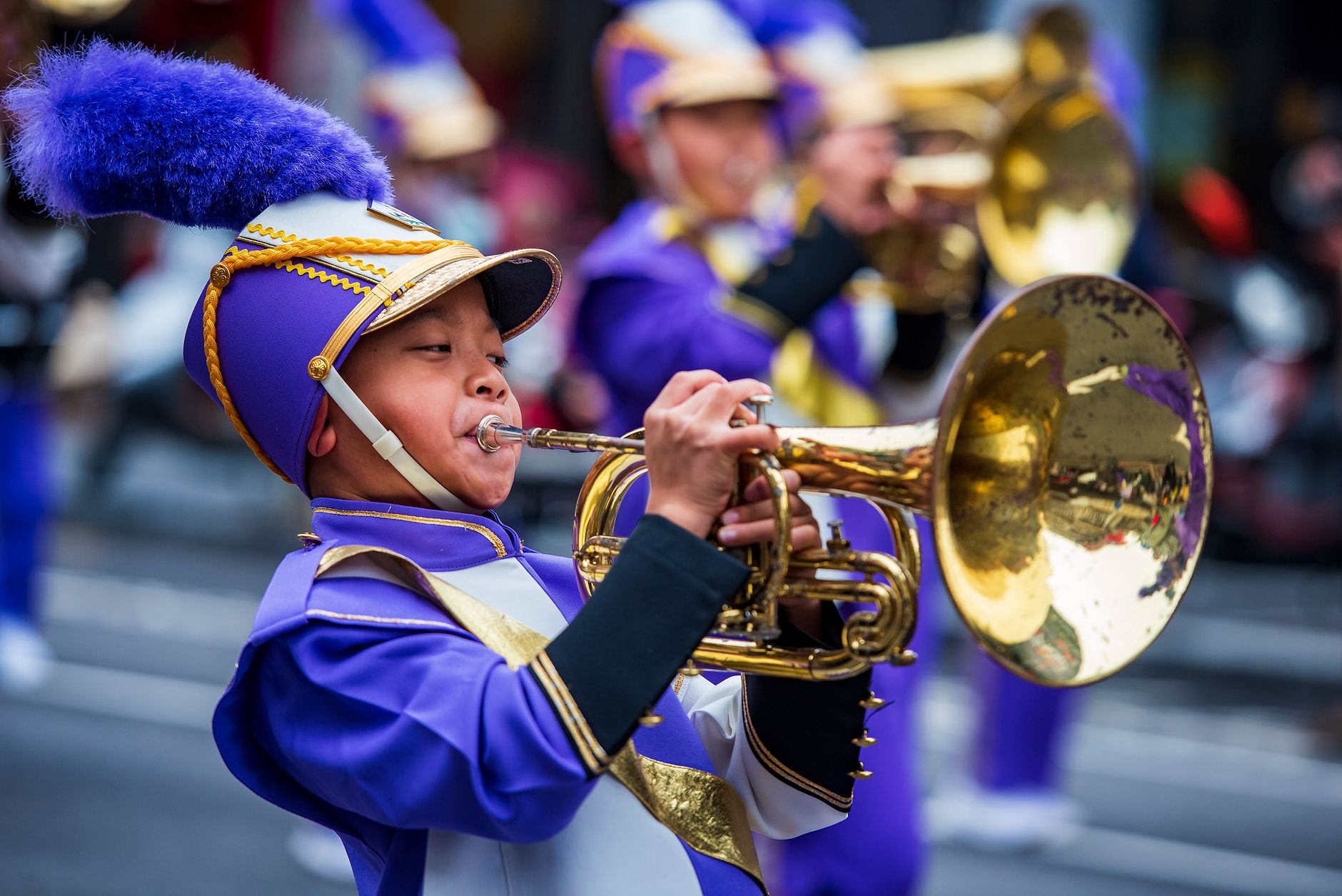 A young boy plays the trumpet in traditional clothing during a colorful parade in Taiwan.