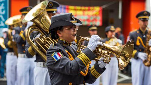 Free Uniformed musicians perform in a parade, featuring a trumpet player in focus. Stock Photo