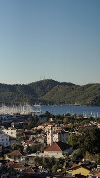 Aerial photo showcasing Fethiye harbor, buildings, and lush hills on a clear day in Türkiye.