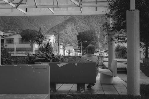 Man Sitting on a Bench in Black and White