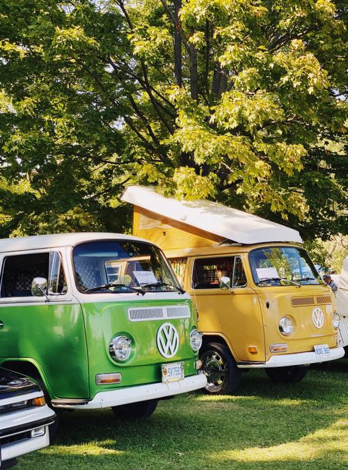 Free Two vintage Volkswagen campers parked in a vibrant, sunlit park during springtime. Stock Photo