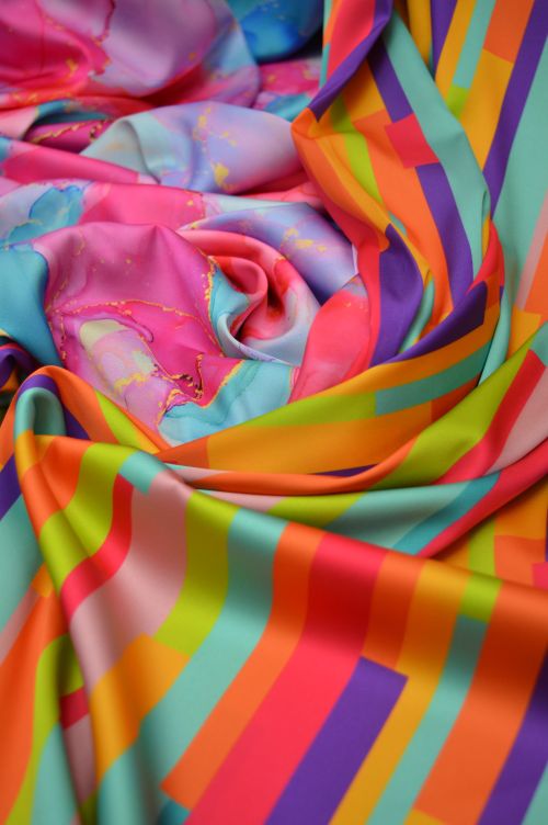Free A vivid display of swirling colorful fabric with geometric patterns. Stock Photo
