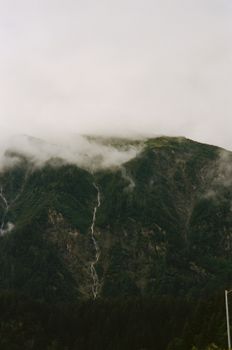 A serene view of a mist-covered mountain with a cascading waterfall.