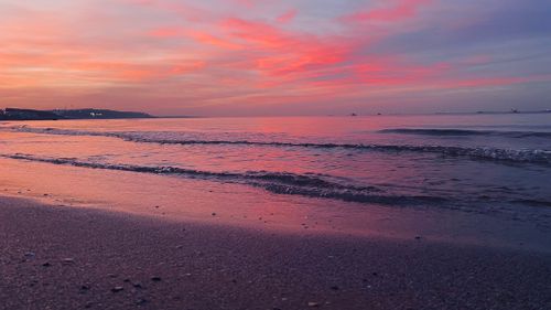 Free Vibrant sunset over gentle ocean waves on a peaceful beach. Stock Photo