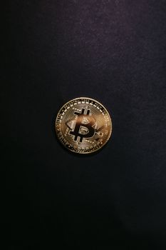 Close-up of a shiny gold bitcoin on a black background, symbolizing cryptocurrency.