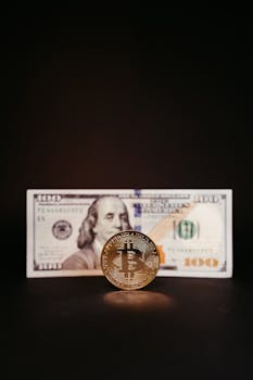 Close-up of a Bitcoin coin in front of a US hundred-dollar bill against a dark background, concept of digital and traditional currency.