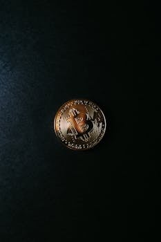 A gold Bitcoin coin placed on a black surface, symbolizing digital currency and blockchain technology.