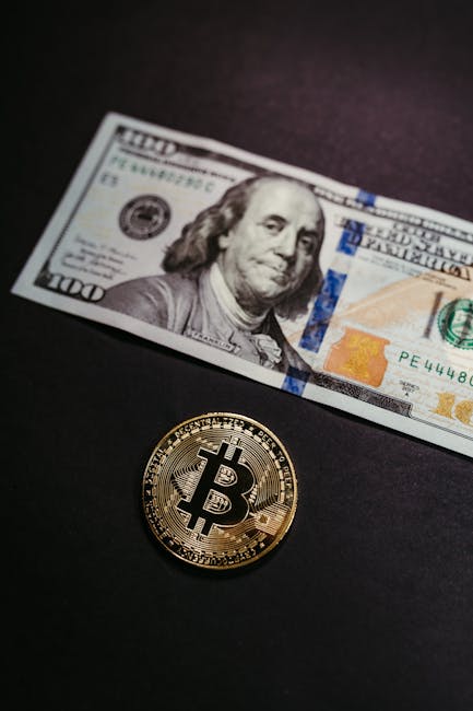 Close-up of a Bitcoin coin with a US 100 dollar bill, symbolizing digital and traditional currency.