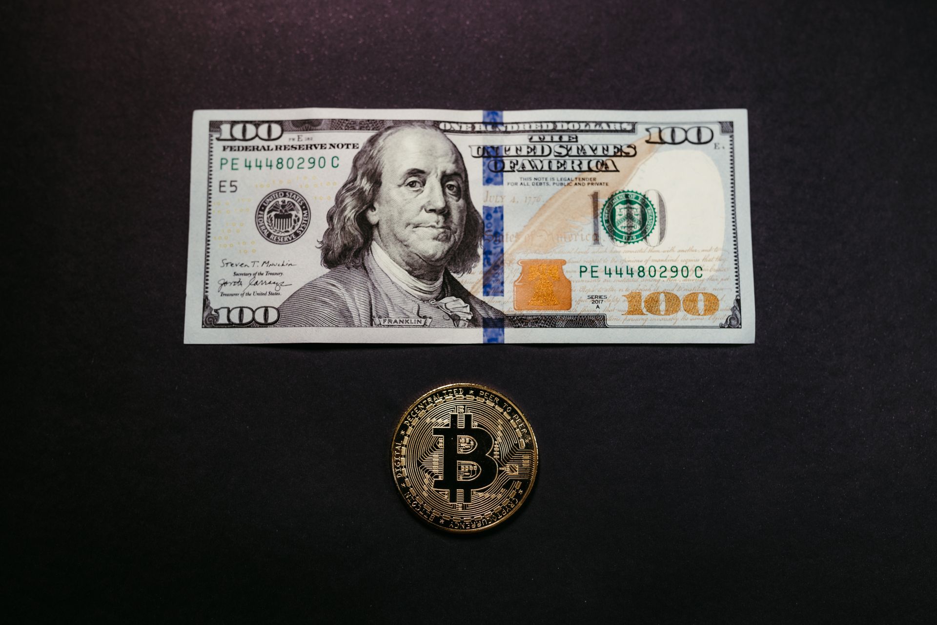 Close-Up Shot of Paper Money and Bitcoin on Black Surface