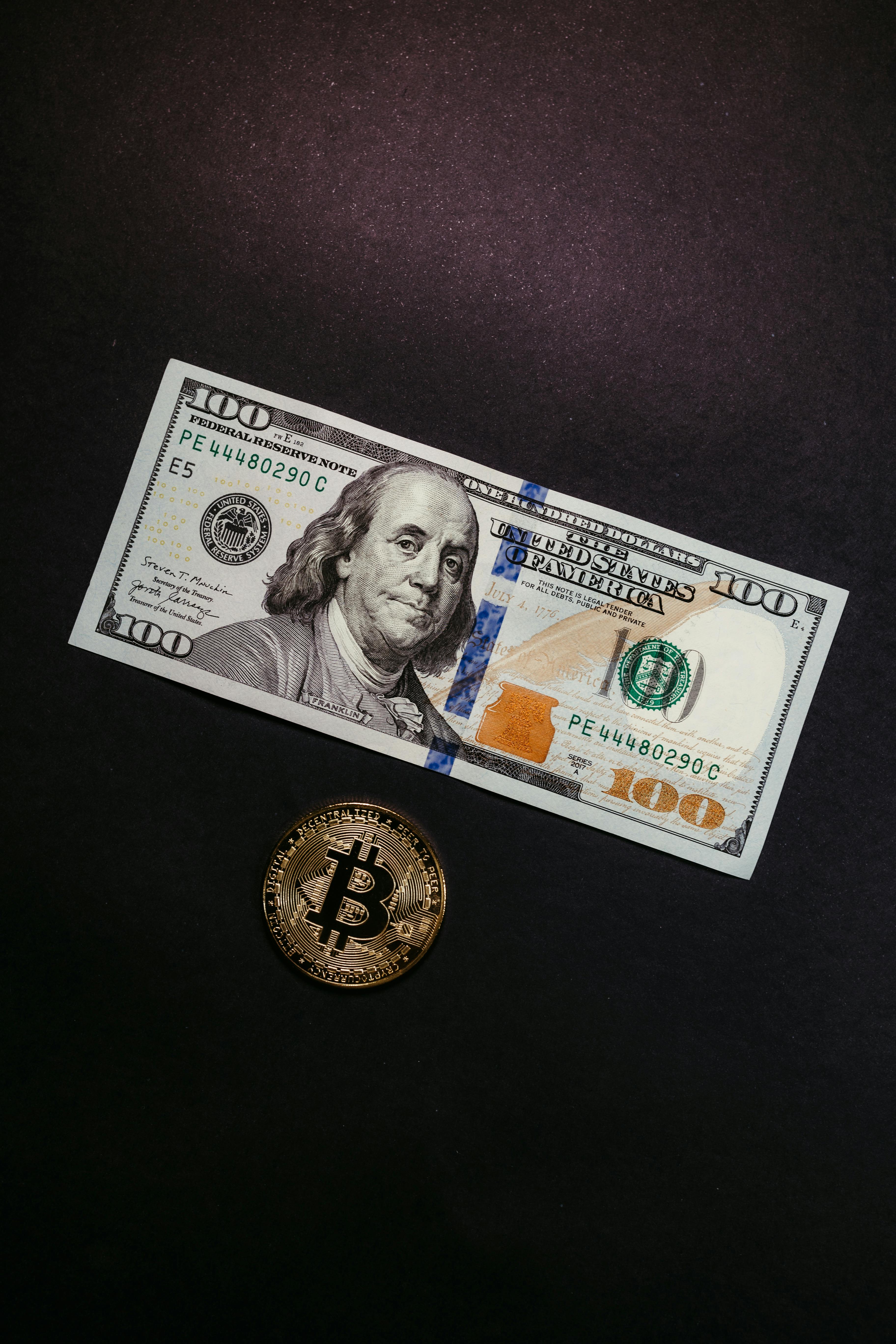 a dollar bill and bitcoin on black background