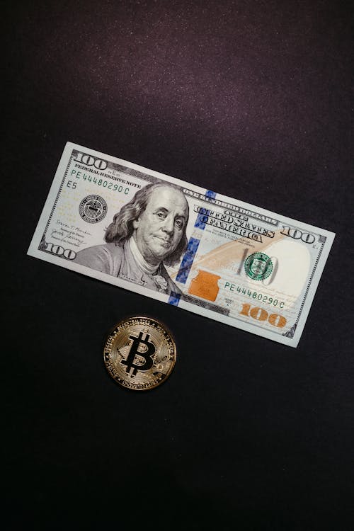 A Dollar Bill and Bitcoin on Black Background