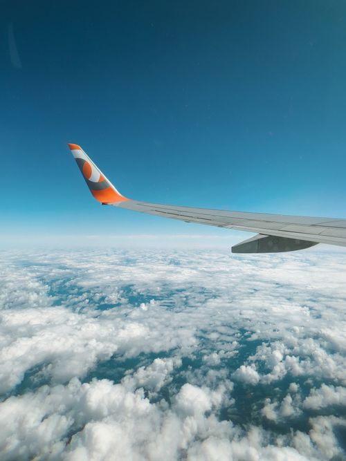 Free Airplane wing over fluffy clouds against a clear blue sky during flight. Stock Photo