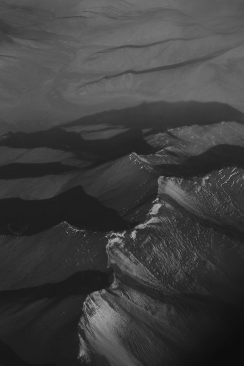 Free Aerial view of rugged mountains captured in black and white, showcasing dramatic shadows and light. Stock Photo