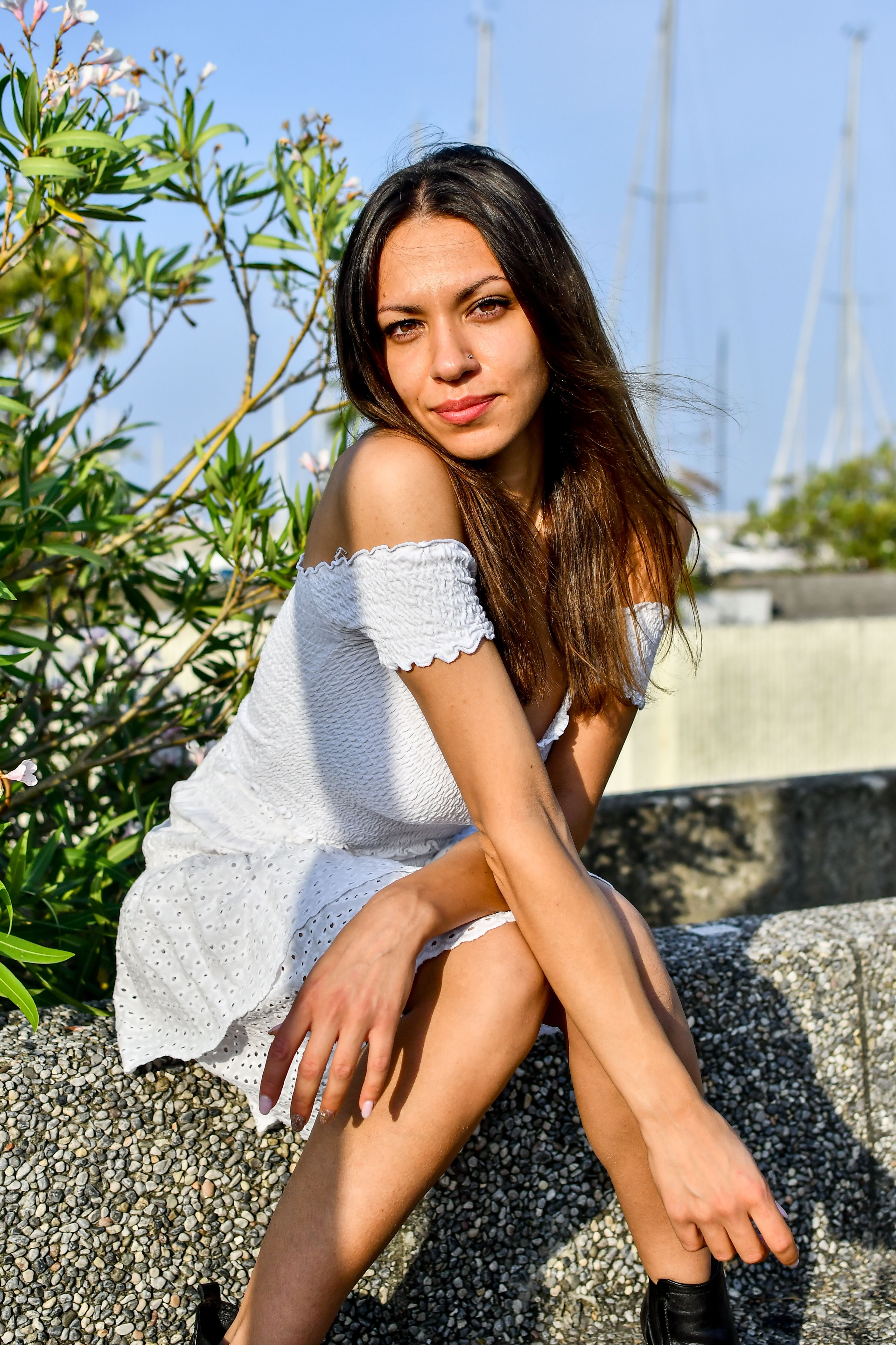 A young woman in a white dress sitting outdoors enjoying a sunny day.