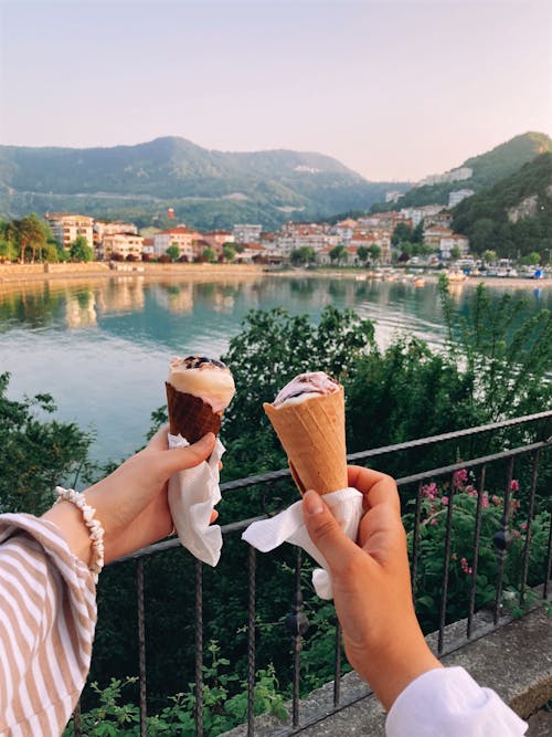 Hands Holding Ice Creams with Lake behind