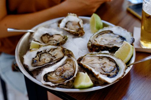 Free A plate of fresh oysters on ice served with lemon slices, perfect for seafood lovers. Stock Photo