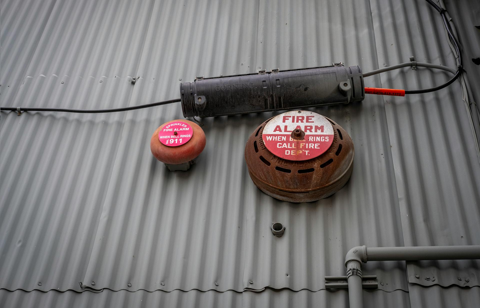 An industrial fire alarm system mounted on a corrugated metal wall for safety and security.