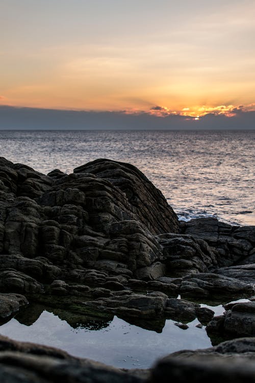Free Rocks on Sea Shore at Sunset Stock Photo